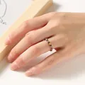 Detailed view of 2mm rainbow tourmaline beaded ring worn on hand with gold lucky coin charm - Faceted Tourmaline