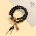 Handmade green sandalwood mala bracelet featuring colorful carved beads and a silk tassel - Ebony Bodhi Style