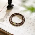 Green sandalwood Buddha beads bracelet with jade charm displayed on traditional calligraphy paper - Golden Thread Sandalwood Multi-wrap Bracelet