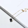 Elegant gold chain bracelet featuring a single polished black bead on a white book - Gold Plated - Obsidian
