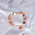 Handmade multi-color gemstone bracelet with gold star charm on grey silk background - Multicolor Tourmaline