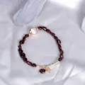 Elegant dark red garnet beaded bracelet with gold star charm and a pink stone detail - Garnet