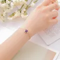 Elegant gold-plated bracelet with round purple amethyst gemstone on model wrist - Amethyst