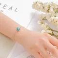 Elegant gold-plated chain bracelet featuring a round turquoise stone on wrist - Turquoise