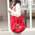 Red linen tote bag with white 'C'est vous' printed lettering worn by a model outdoors - Red