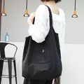 Detalle de un bolso de lona negro con una pequeña B bordada en el bolsillo - Estilo de Bolsillo Abierto con Letra B Bordada (SRA773)