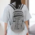 Minimalist grey grid nylon backpack with drawstring detail shown on model back. - Gray