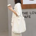 Stylish white canvas tote bag featuring black polka dots and a drawstring closure. - White