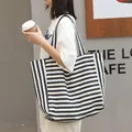 Stylish navy blue and white striped canvas tote bag for women in a casual street setting. - Blue