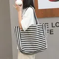 Casual black and white striped canvas tote bag for women in a lifestyle setting - Black