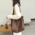 Large minimalist brown suede drawstring tote bag with pleated detail shown on model. - Coffee