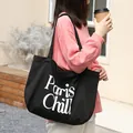 Vista detallada del bolso de lona negra con estampado Paris Chill y atuendo informal - Estilo de Lona con Estampado Paris Chill (SR5555)