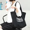 Elegante bolso de lona negra con estampado gráfico, llevado por una modelo - Estilo Tote de Hombro con Líneas Geométricas (SRA775)