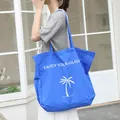 Casual blue nylon tote bag with white palm tree print and holiday slogan text. - Blue