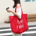 Stylish large red nylon tote bag featuring white Perpétuité letter print on urban street background - Red