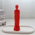 Close-up of a red male figure candle placed on a minimalist white oval tray - Male Body / Red