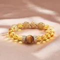 Elegante pulsera de citrino y cuarzo rutilado dorado sobre fondo de seda rosa - Lucky Overlord Natural Estilo A