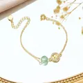 Detailed close-up of gold Tree of Life bracelet with green rutilated quartz on mirror - Green Strawberry Quartz Tree of Life