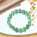 Elegant close-up of green crystal bead bracelet with gold spacers on a reflective mirror - Green Strawberry Quartz Bracelet