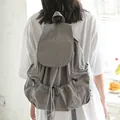 Minimalist grey nylon drawstring backpack with unique pleated design and side pockets - Gray