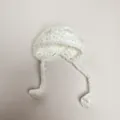 Close-up of white handmade knitted mini doll hat with ties and decorative pom-poms - Pure White