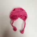 Detailed macro view of a handmade pink crochet mini hat with ties for doll dress-up - Rose Red