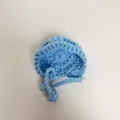 Close-up of light blue mini crochet doll hat with hand-knitted texture and ties - Light Blue