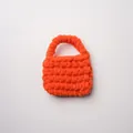 Vista detallada de un mini bolso de punto grueso naranja brillante hecho a mano con lana - Naranja