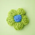 Handgefertigtes grünes Häkelblumen Accessoire mit blauem Zentrum für Kleidung und DIY-Projekte - Grün und Blau