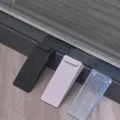 Detail view of three non-slip stackable wedge door stoppers in black, pink, and blue - 1 Piece / White
