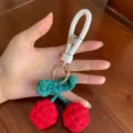 Primo piano di un portachiavi a forma di ciliegia rossa lavorato a mano con cinturino bianco - Ciondolo per Auto / Taglia S / Rosso