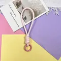 Gedetailleerde macro-opname van lichtroze gevlochten polsbandje met metalen ring - Telefoonsnoer / 1 Stuk / Lichtroze