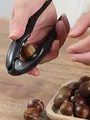 Manual black chestnut opener and nutcracker tool being used to shell fresh chestnuts - Black