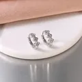 Close-up of stainless steel hoop earrings with delicate flower pattern set with crystals. - Rhinestone Clover Ear Clip / Steel