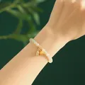 Elegantes Armband aus natürlicher Hetian-Jade mit goldenen Lotus-Anhängern am Handgelenk - Weißer Jade