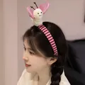 Serre-tête papillon en peluche mignon porté par un modèle avec des accents rose doux - Design Papillon