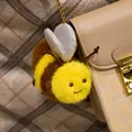 Lindo llavero de abeja de peluche con alas brillantes colgado de un bolso beige. - Llavero Abeja / 10cm