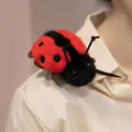 Mignon accessoire d'épaule en peluche coccinelle rouge et noire sur une chemise crème. - Fixation Épaule Coccinelle