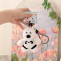 Primo piano di un simpatico portachiavi in peluche di cane bianco in una mano. - Panda / 12cm