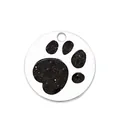 Close-up of circular metal pet ID tag with black glitter paw print design on white background. - Dog Paw Print (HC485) / Black