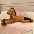 Large brown plush horse toy with decorative tassels lying on a cozy pink blanket. - 90cm / Brown