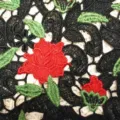 Detailed macro view of high-quality water-soluble lace fabric with red rose 3D embroidery - Black/Red/Green