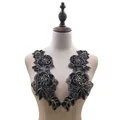 Macro view of black rose floral embroidery patches with gold outlines on a mannequin - Black & Gold