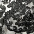 Gros plan sur un tissu de dentelle noire avec broderie florale hydrosoluble raffinée - Noir