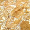 Nahaufnahme von goldenem wasserlöslichem Spitzengewebe mit Paisley- und Blumenstickerei. - Gold