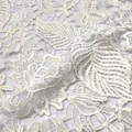 Close-up of white water-soluble lace fabric with detailed 3D leaf and flower embroidery - White
