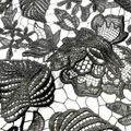 Macro view of black water-soluble lace fabric showing detailed leaf embroidery patterns - Black
