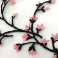 Macro view showing detailed pink cherry blossom and black branch embroidery on fine mesh fabric - Pink and Black