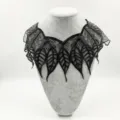Detail view of a black water-soluble lace collar featuring delicate leaf embroidery. - Black