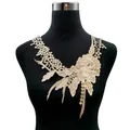 Detailed view of champagne gold water-soluble lace floral embroidery on a black mannequin. - Coffee